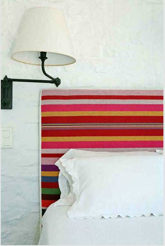 Colorful horizontal stripped bed with white pillow and blanket and lamp in the bedroom.