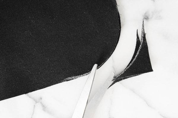 A person is cutting cloth edges in curve shape with scissor.