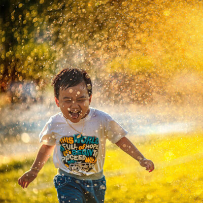 little kid running through a sprinkler