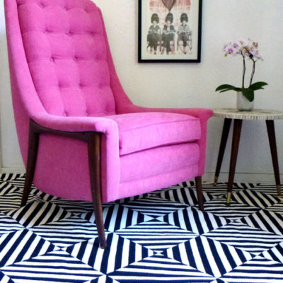 A pink chair sits on black and white striped floor.