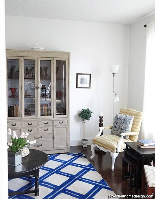 A sitting room with a blue and white carpet and a grey sideboard.
