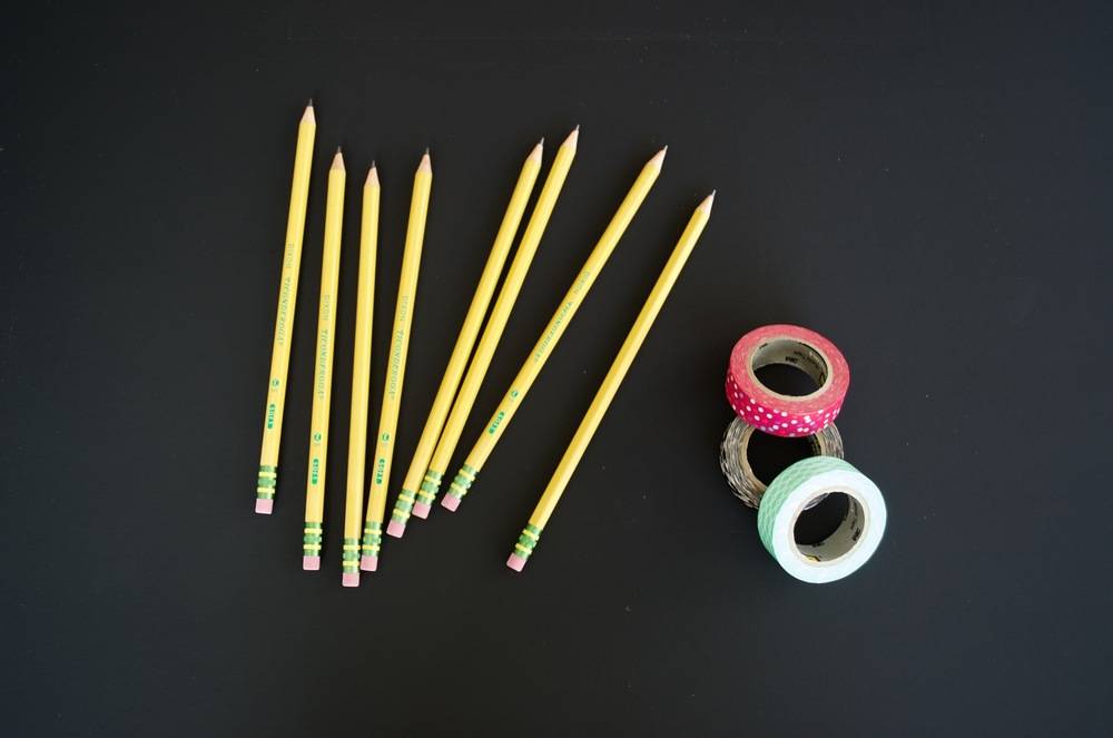 Eight sharped pencil erasers and three colored plasters on the black background.