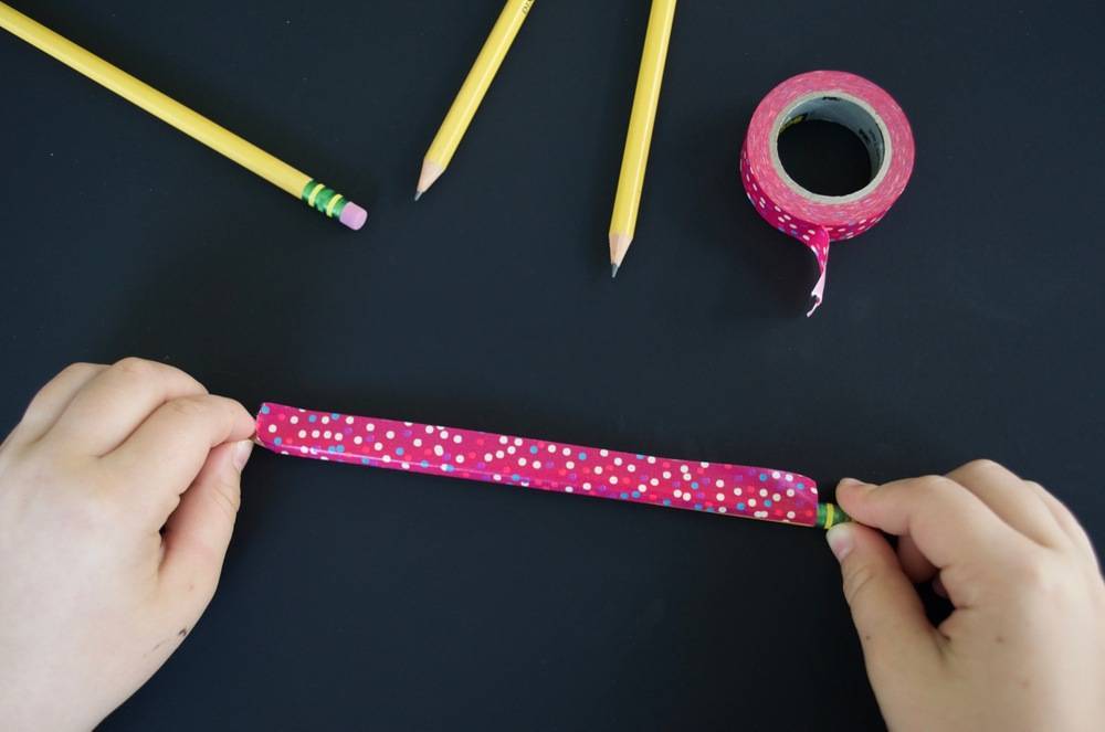 A person is stretching out a piece of pink speckled tape