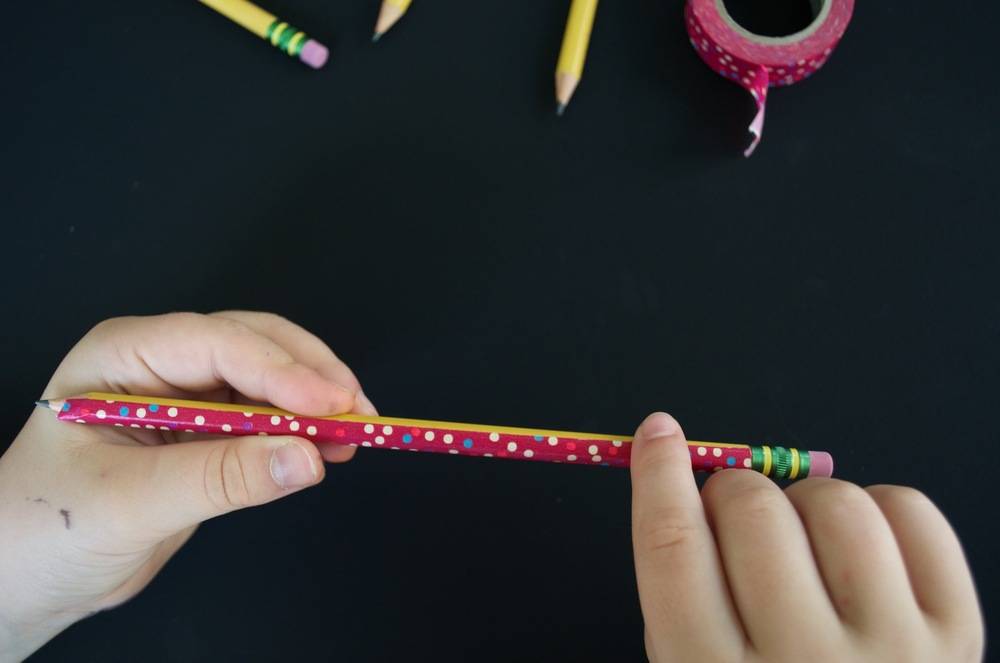 A person doing crafts with colored pencil erasers and designer tapes.