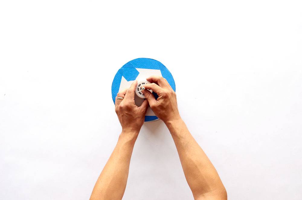 A man applies paint in the middle of a blue taped circle