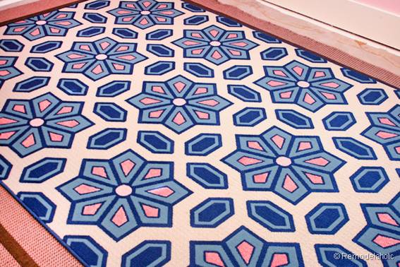 A rug with blue pink and white floral shapes.