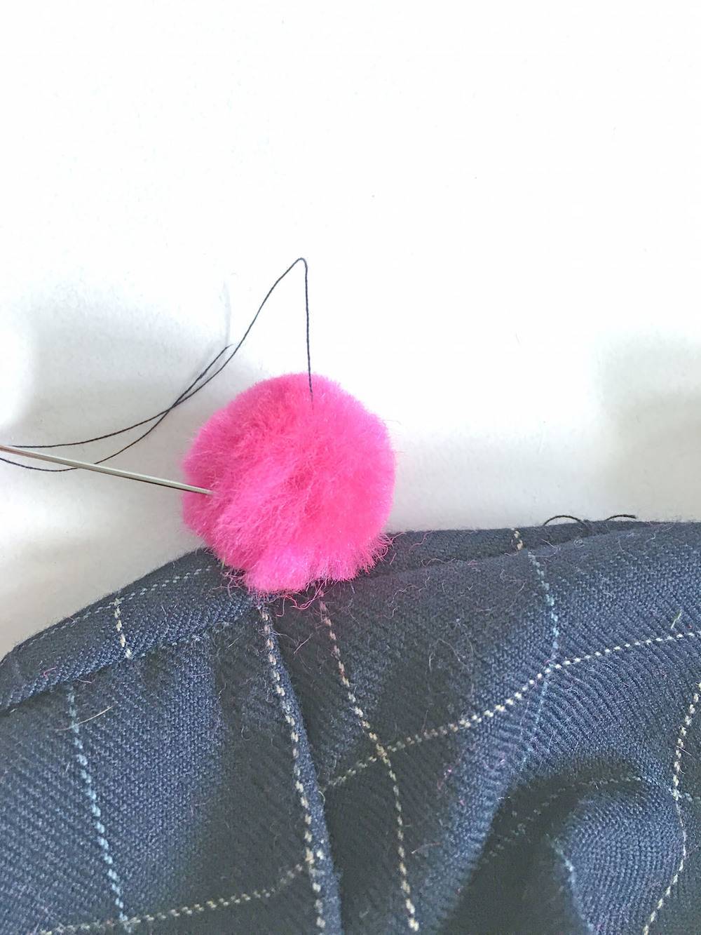 Pink wool with knitting needle and thread on the cloth.