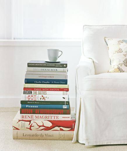 A stack of colorful books next to a white chair