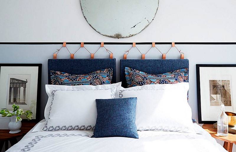 Pillows sit on a white bed with a blue headboard.