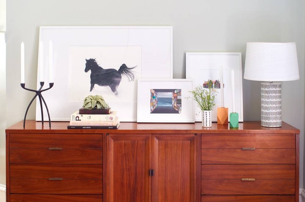 Pictures and plants on a credenza.