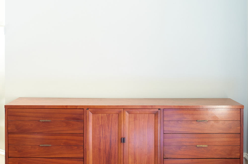 A dresser with drawers and a cabinet is set up against a light colored wall.