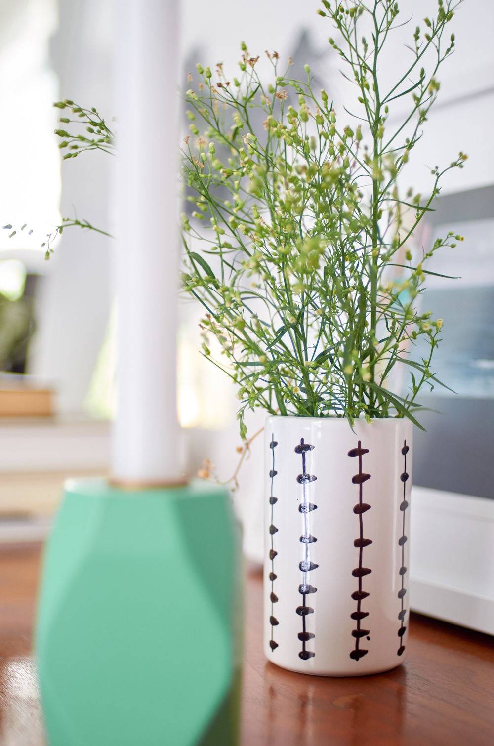 A plant is growing in a white and black vase on a desk.
