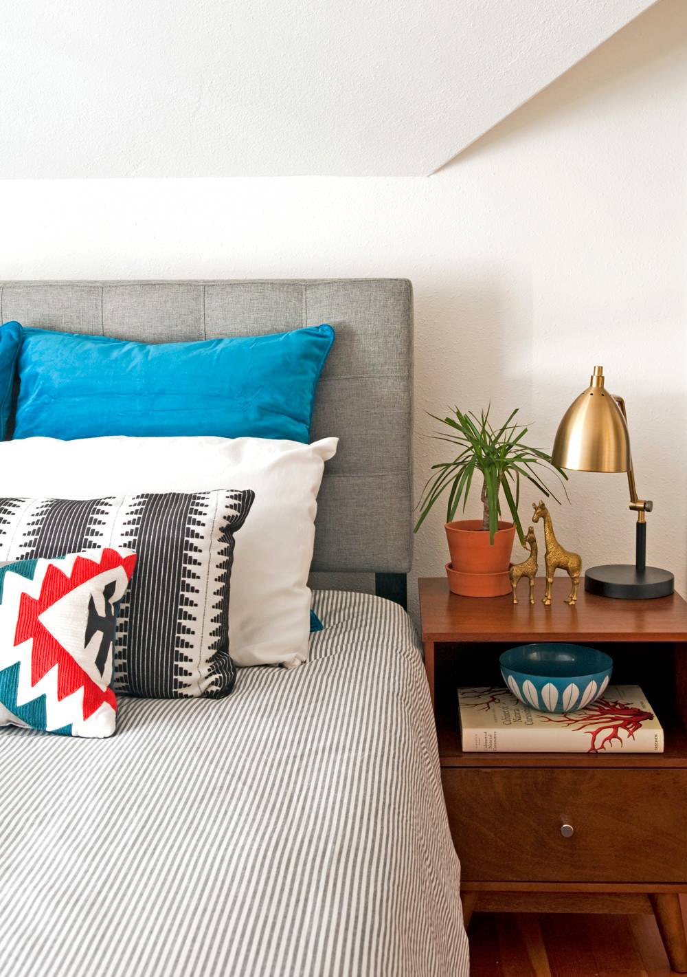 Bedroom along with bed, bed sheet, pillows and table.