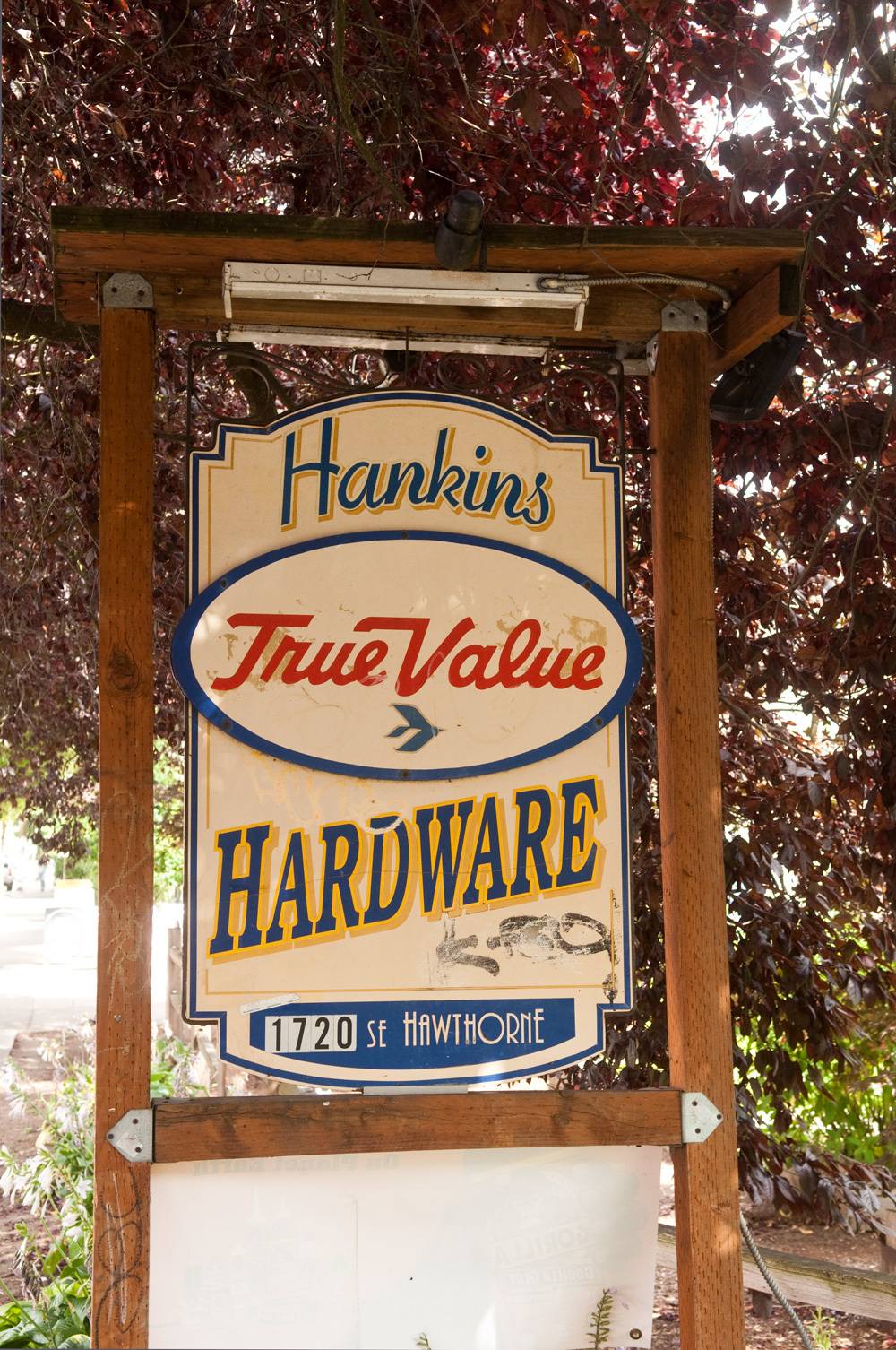 A sign in a wooden frame shows where a hardware store is.