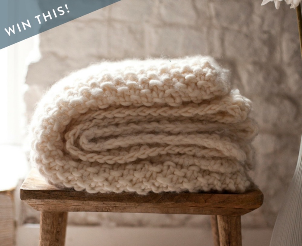 Folded white color blanket knitter on the stool.