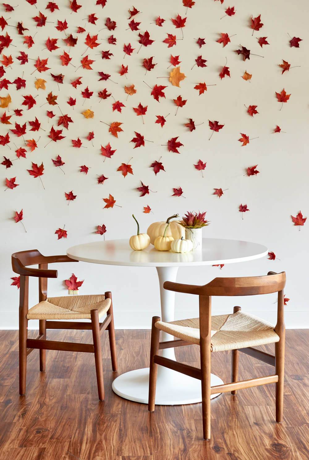 Table and chairs below a wall full of scattered leaves.