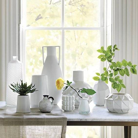 A table has many small white vases on it.
