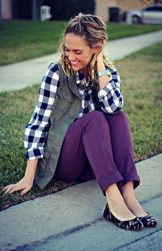 A woman in purple pants sitting on the grass near a road