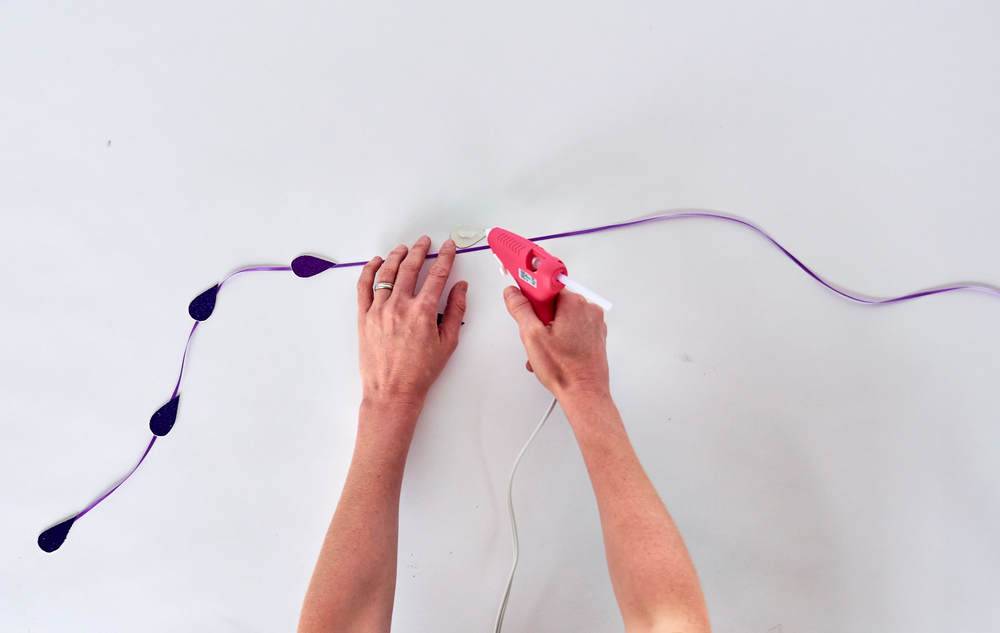 A person is glueing something to a white wall.