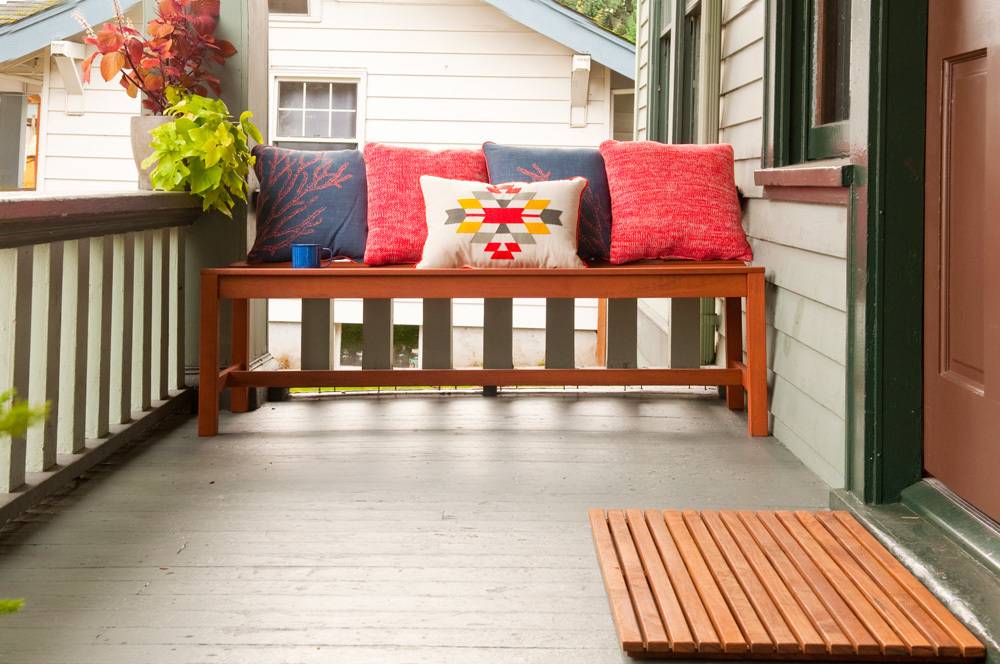 Colorful pillows on a front porch bench.