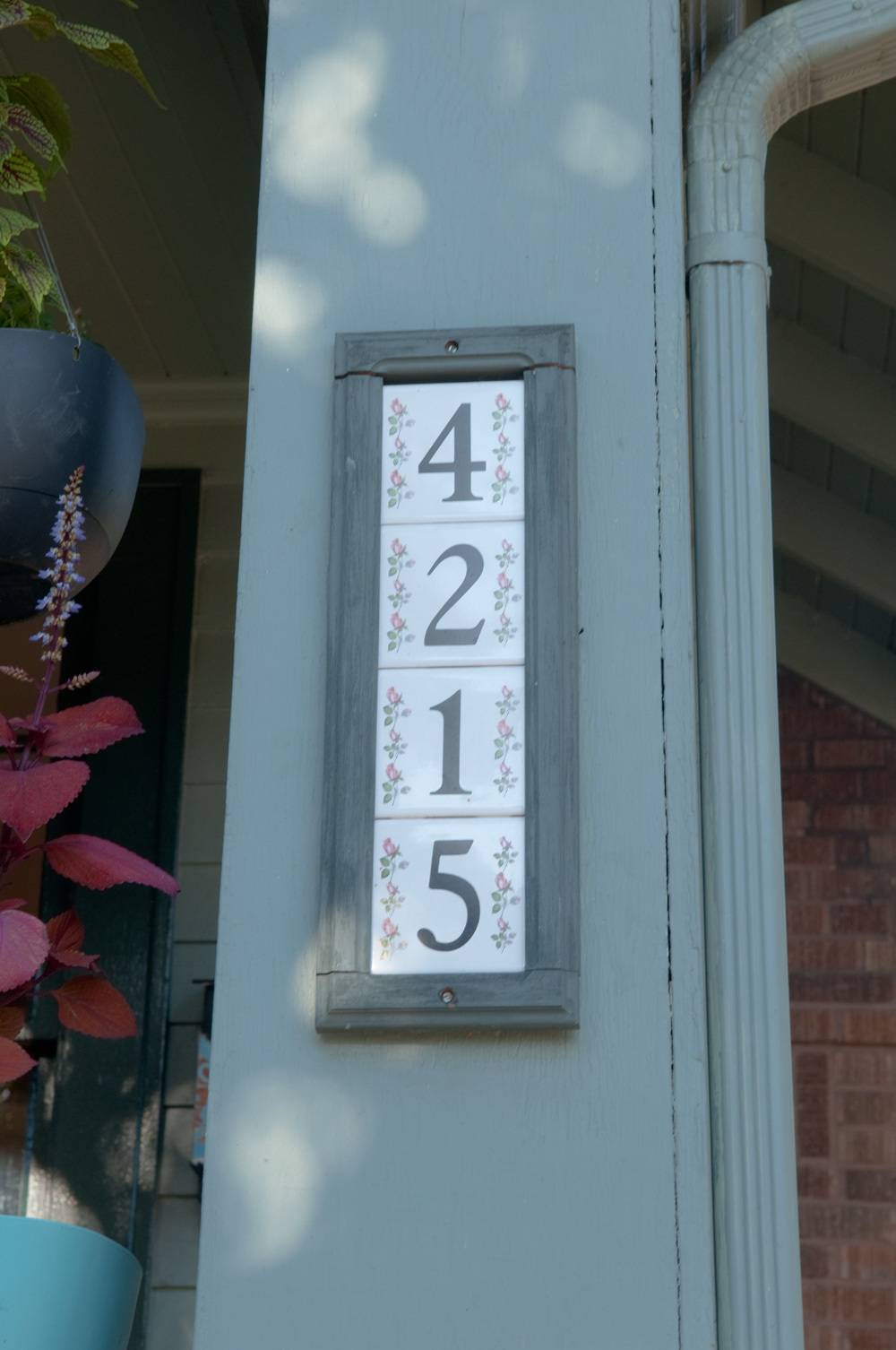 Decorativr tiles with numbers on them by the front door of the house.