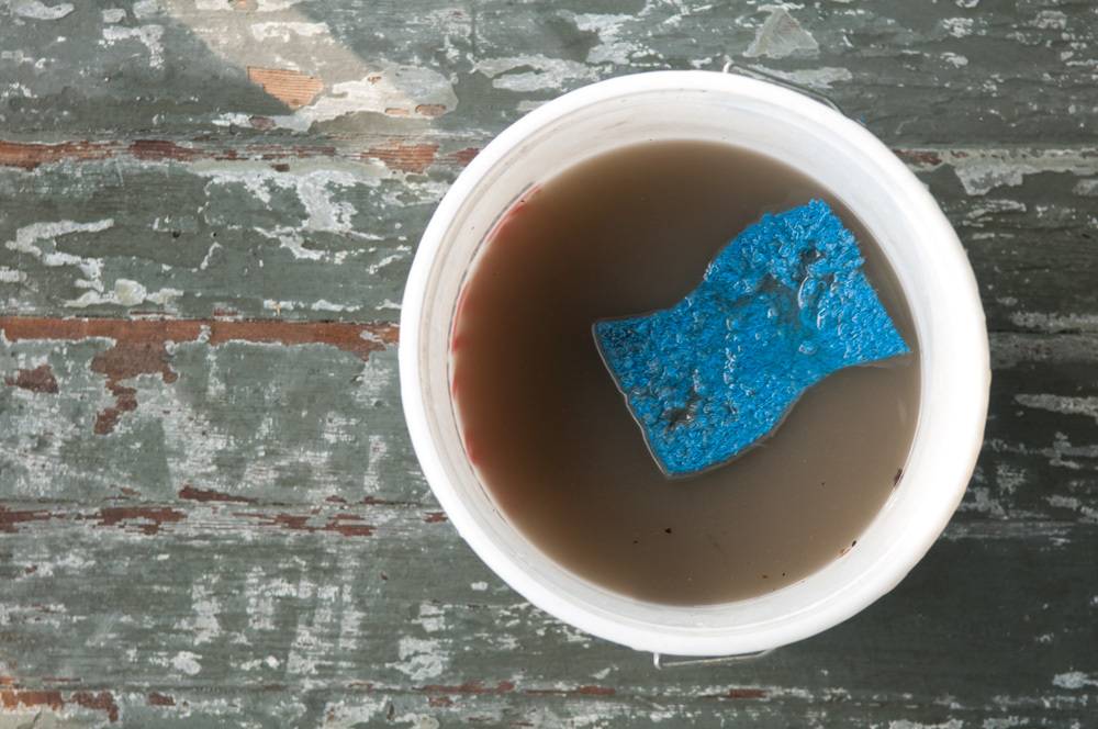 A blue sponge in a cup of coffee on a table.