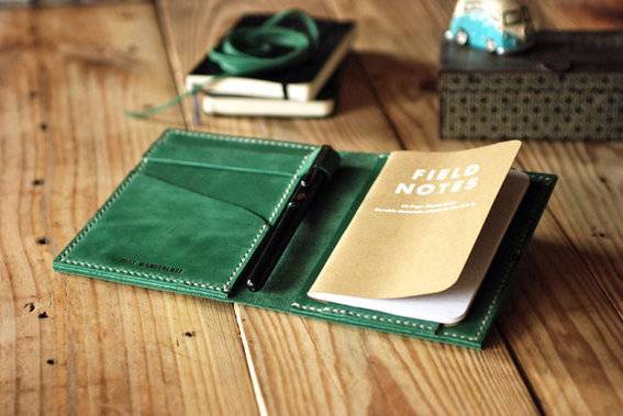 A brown field note book with a green cover.