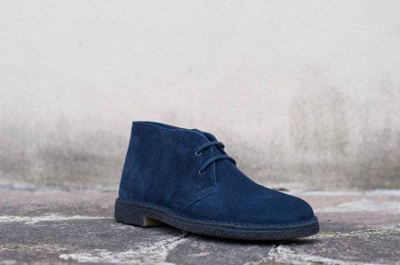 A dark blue suede lace up shoe sits outside.