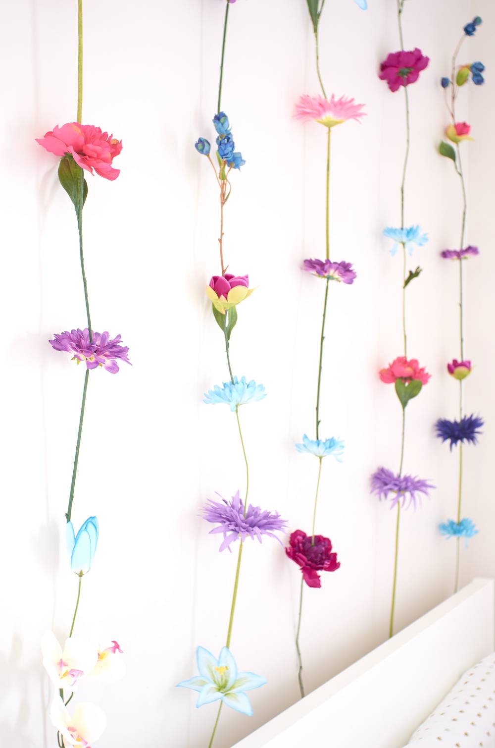 Flowers strung in a vertical line hanging down from ceiling.
