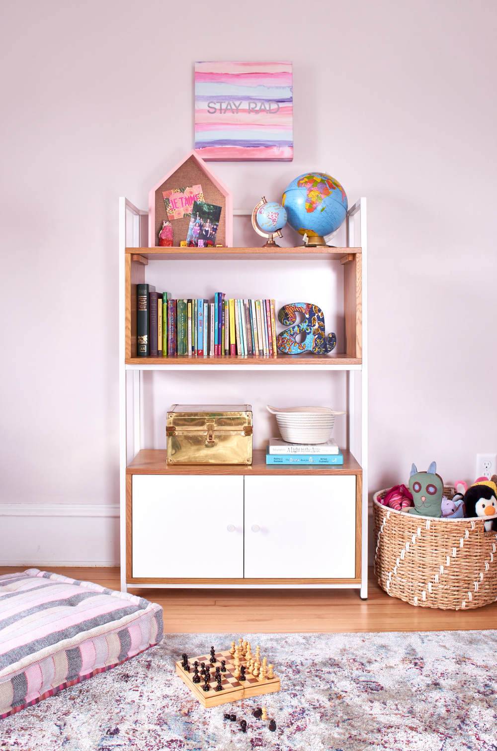 White bookcase in a girls room with pink accents.