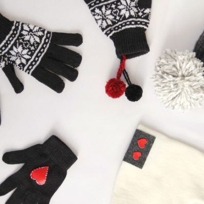 Gloves and hats with hearts are sitting on a white surface.