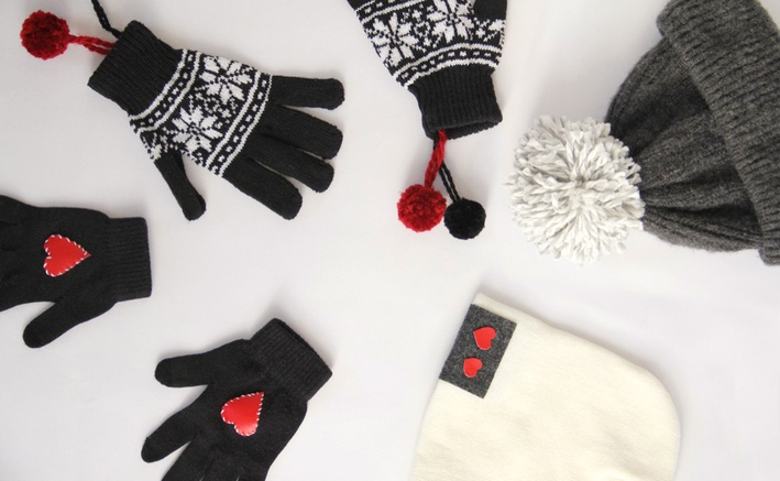 Gloves and hats with hearts are sitting on a white surface.