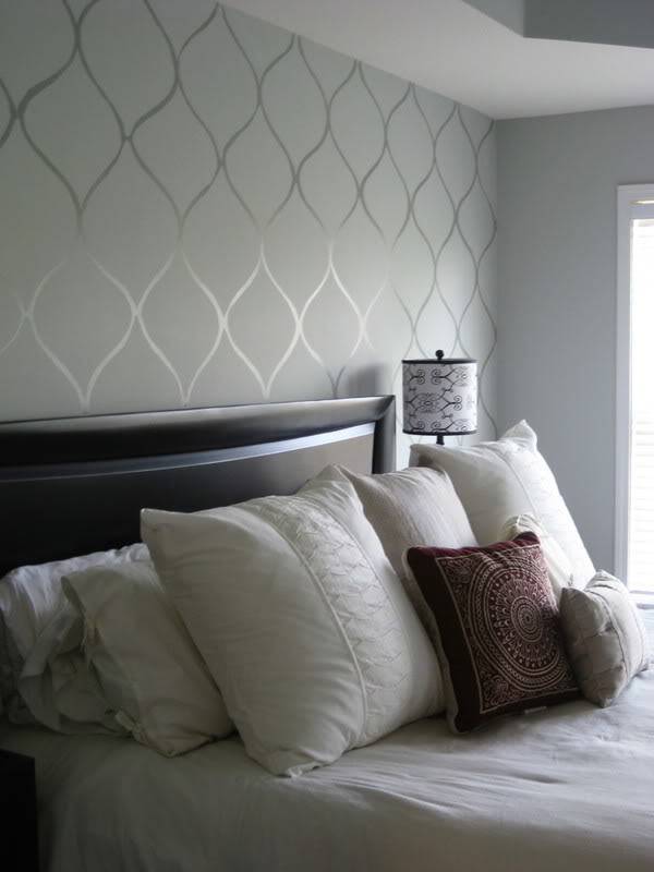 A painted stencil on a bedroom wall above the headboard