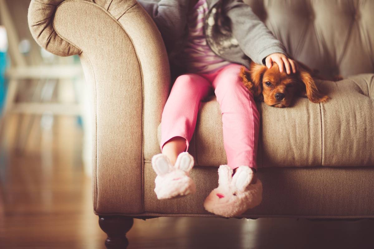 A child with pink pants and bunny slippers is sitting on a couch.