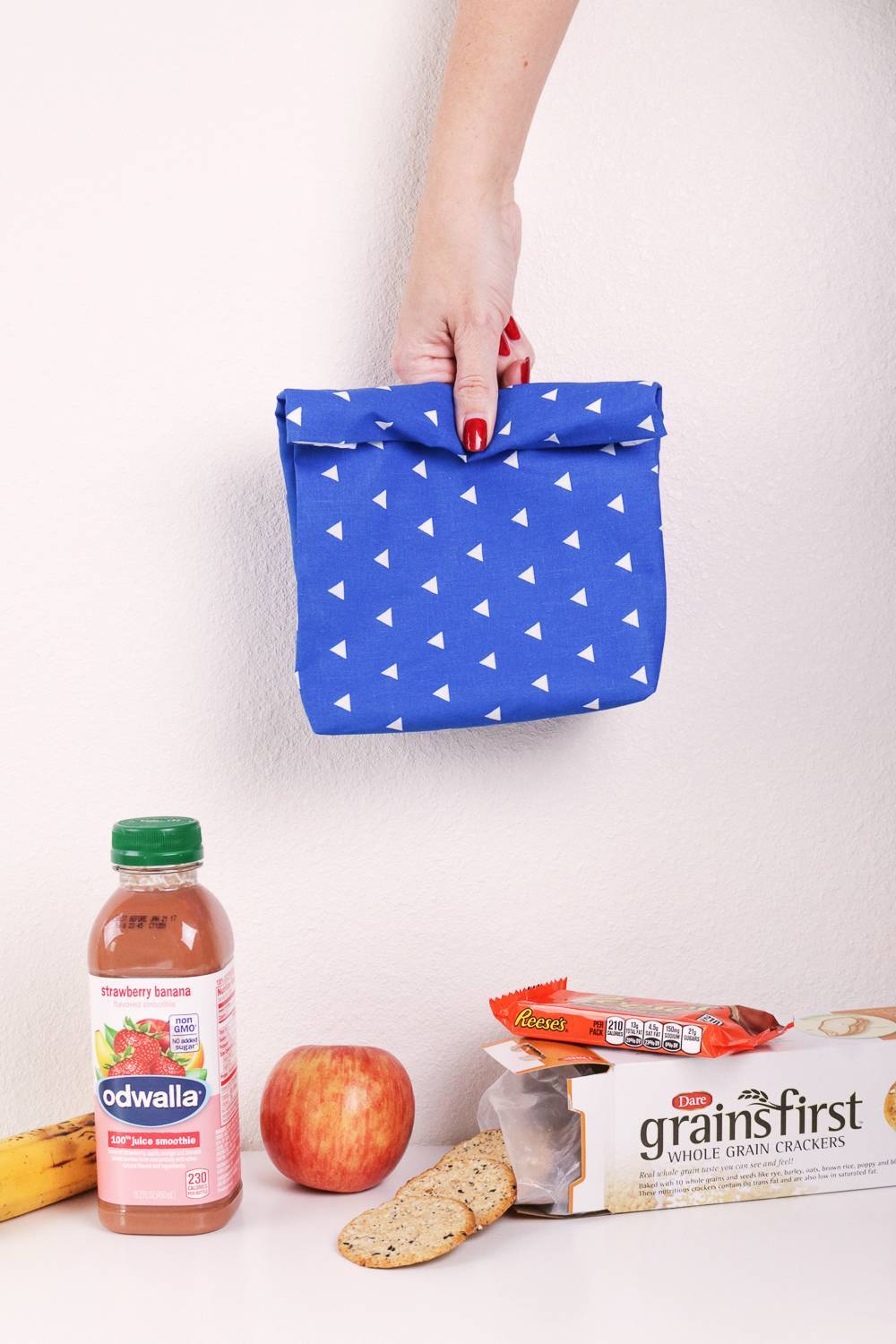 A person holding a blue polka dotted item above groceries.