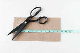 Cardboard with measuring tap and scissor.