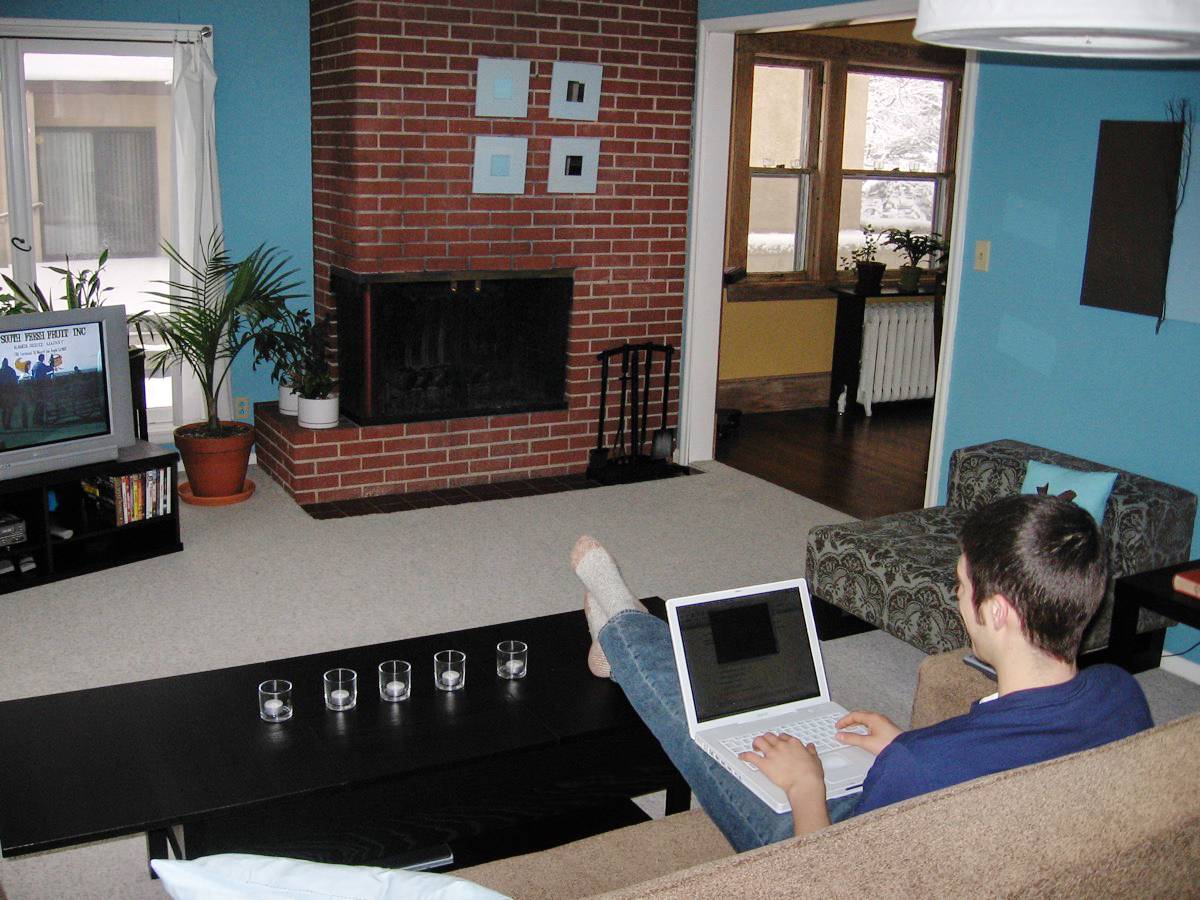 Man sitting on couch with a laptop in a living room.