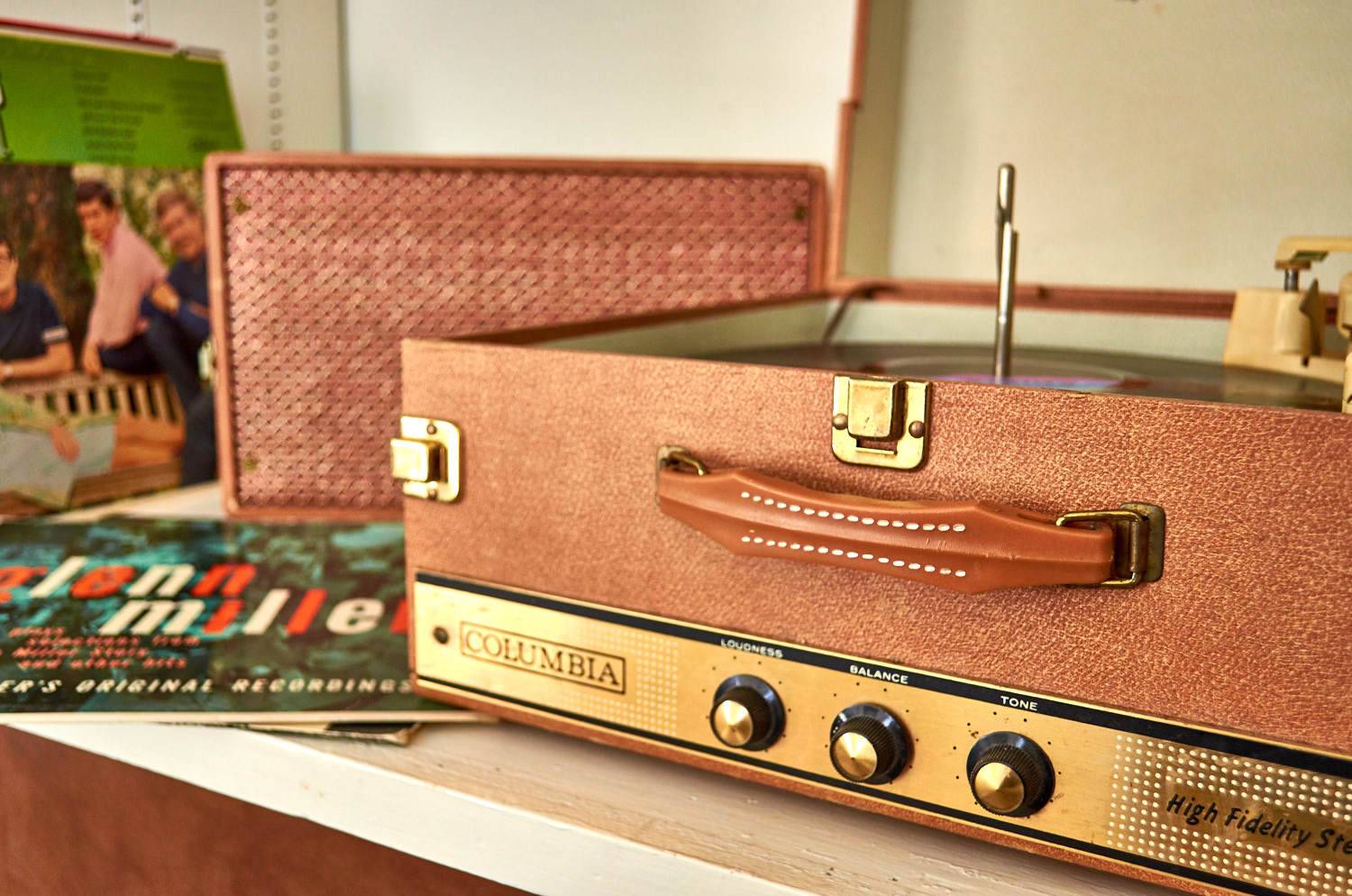 Vinyl records by vintage record player built into a brown suitcase.
