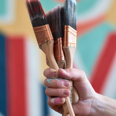 A person holding a handful of paint brushes.