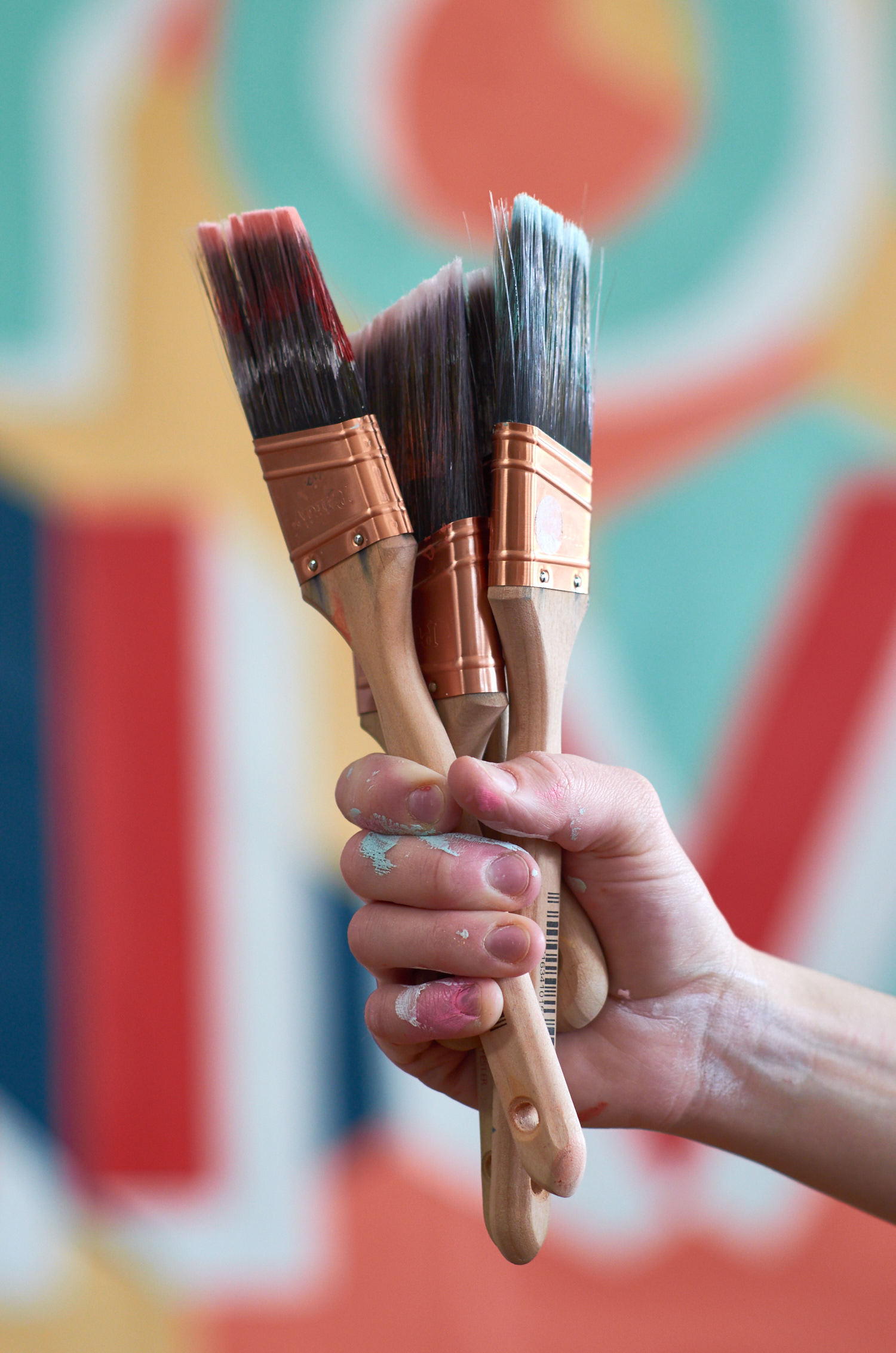 A person holding a handful of paint brushes.