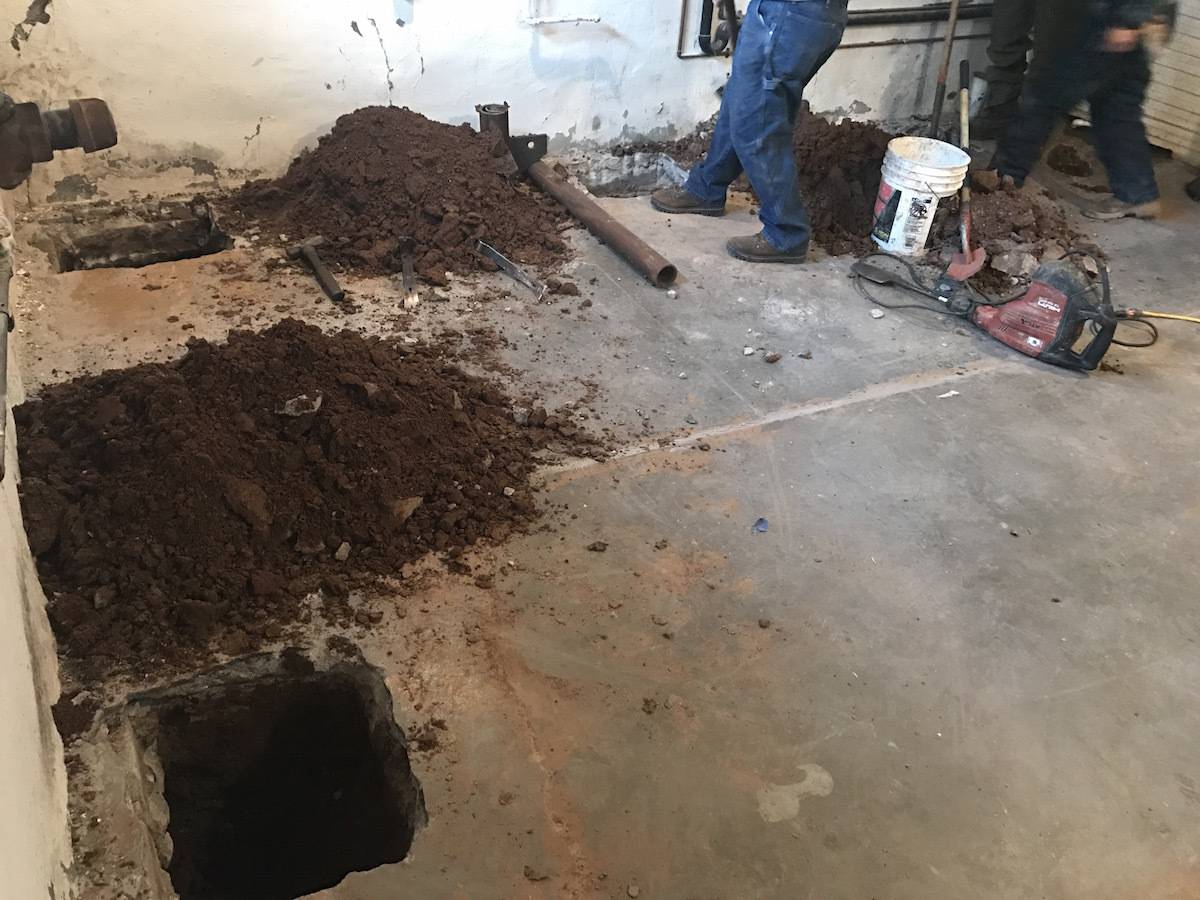 Men are working in a dirty garage with dirt piles.