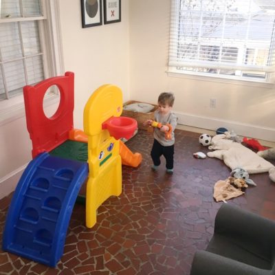 A child is playing on a colorful slide in a living room.