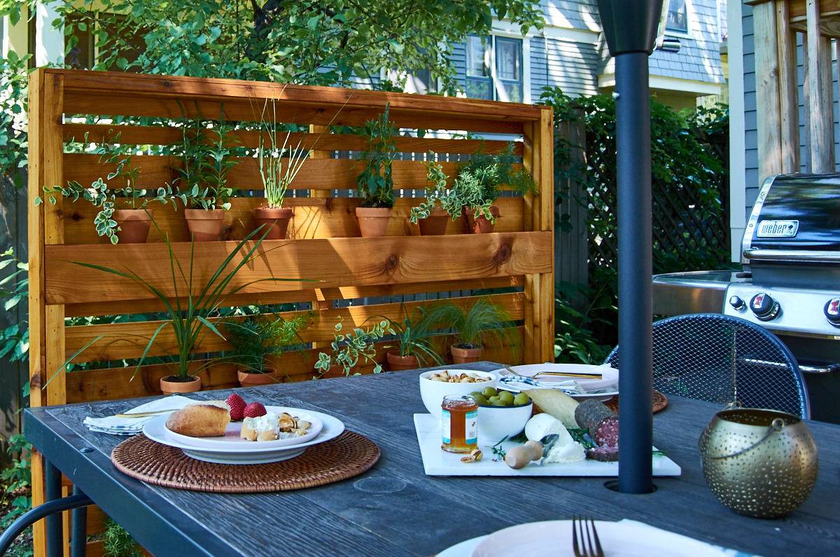 Dinning table with lots of food and potted plants in the wooden rack inside the garden.