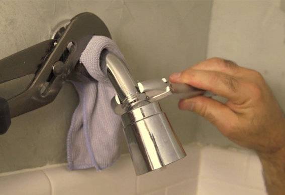 A person is using a wrench on a shower head.