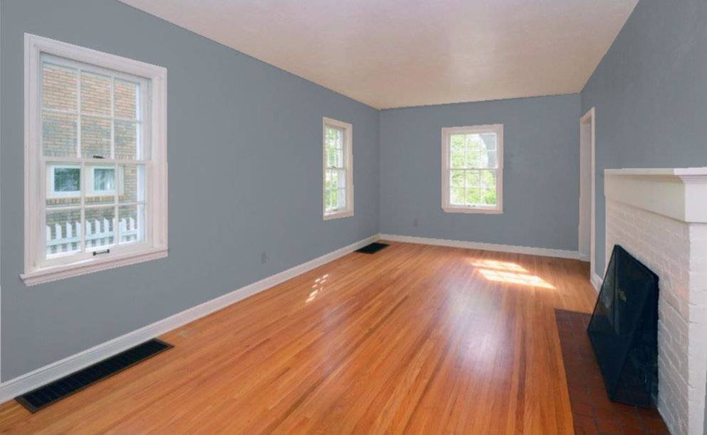 An empty room has blue walls, a hardwood floor and a white brick fireplace.