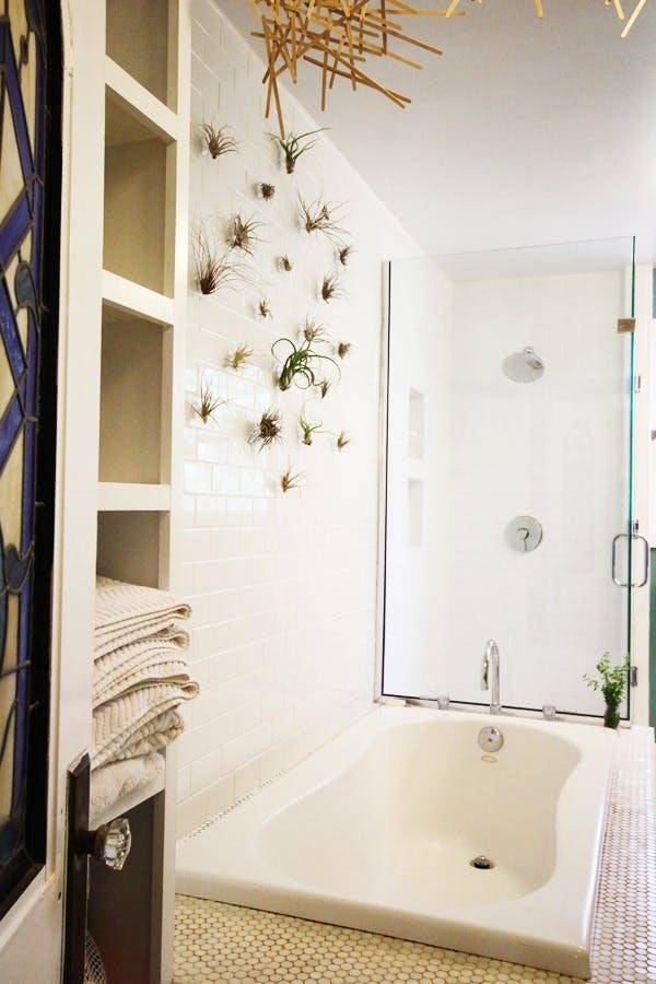 This modern bathroom has a large soaking tub and a shower behind it with a glass door.