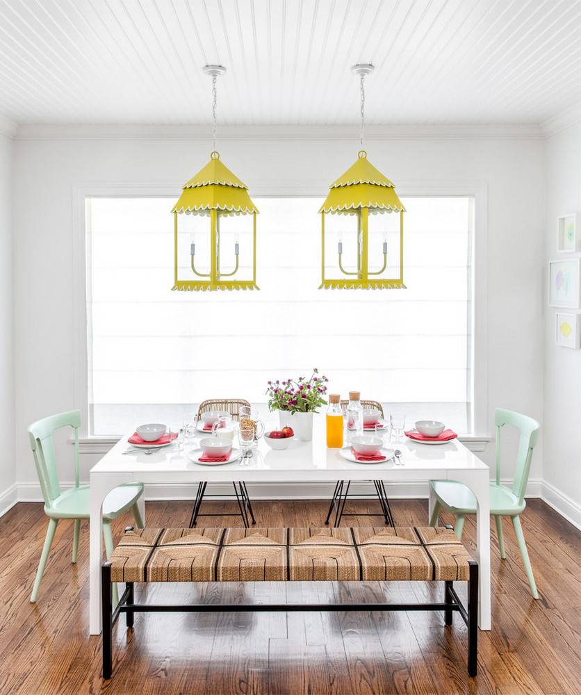 A white table and chairs sit near a window under yellow lights.