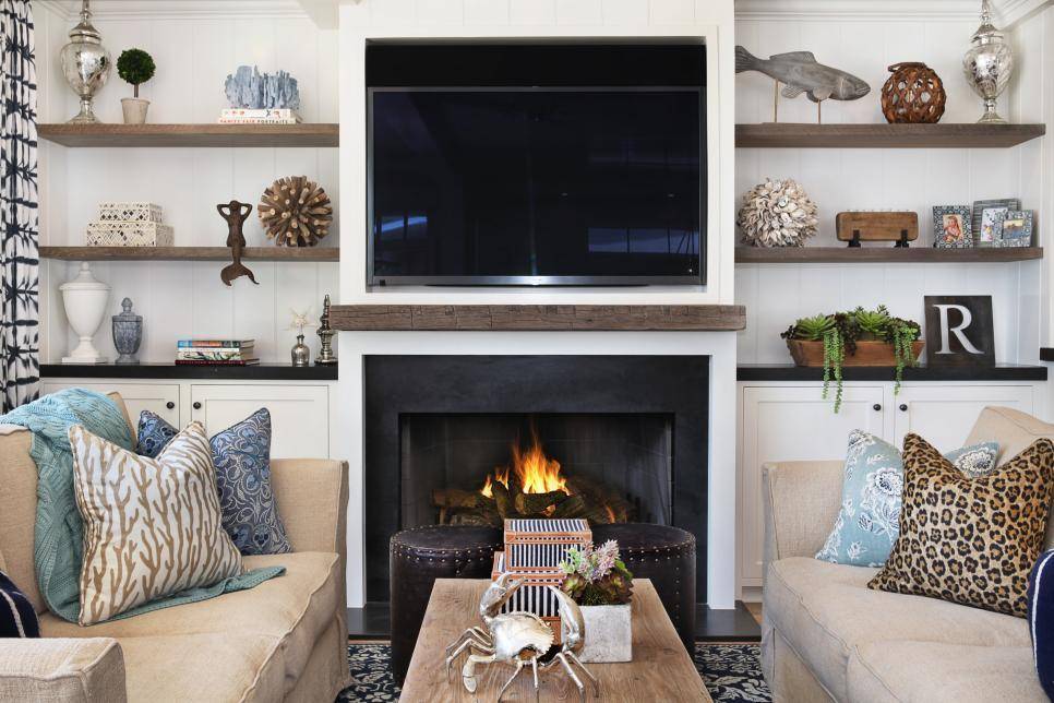 A fireplace, two tan sofas, a golden crab on a tan coffee table and grown shelving filled with chatchkys.