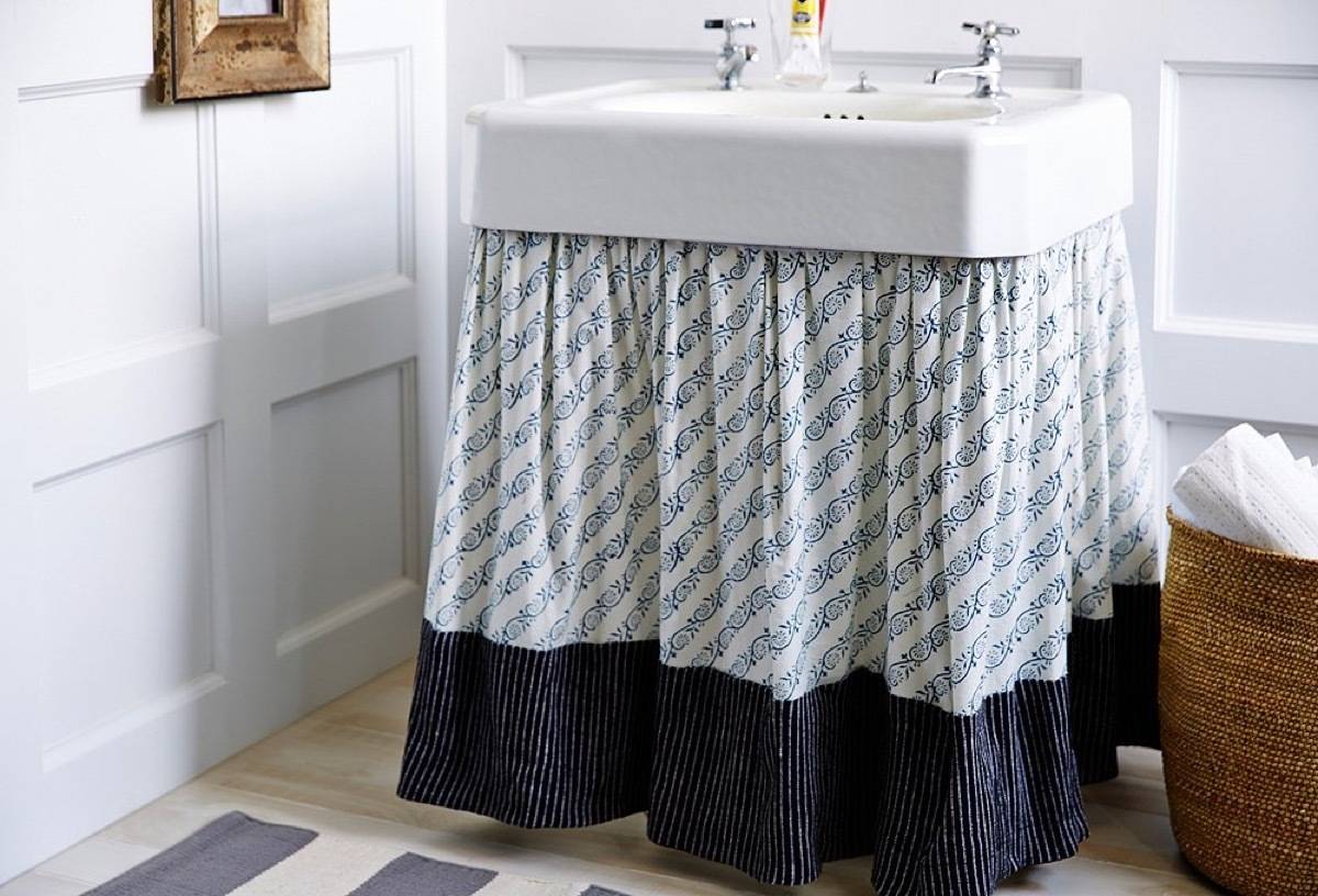 Hang a curtain under a pedestal sink to hide ugly pipes and create more storage