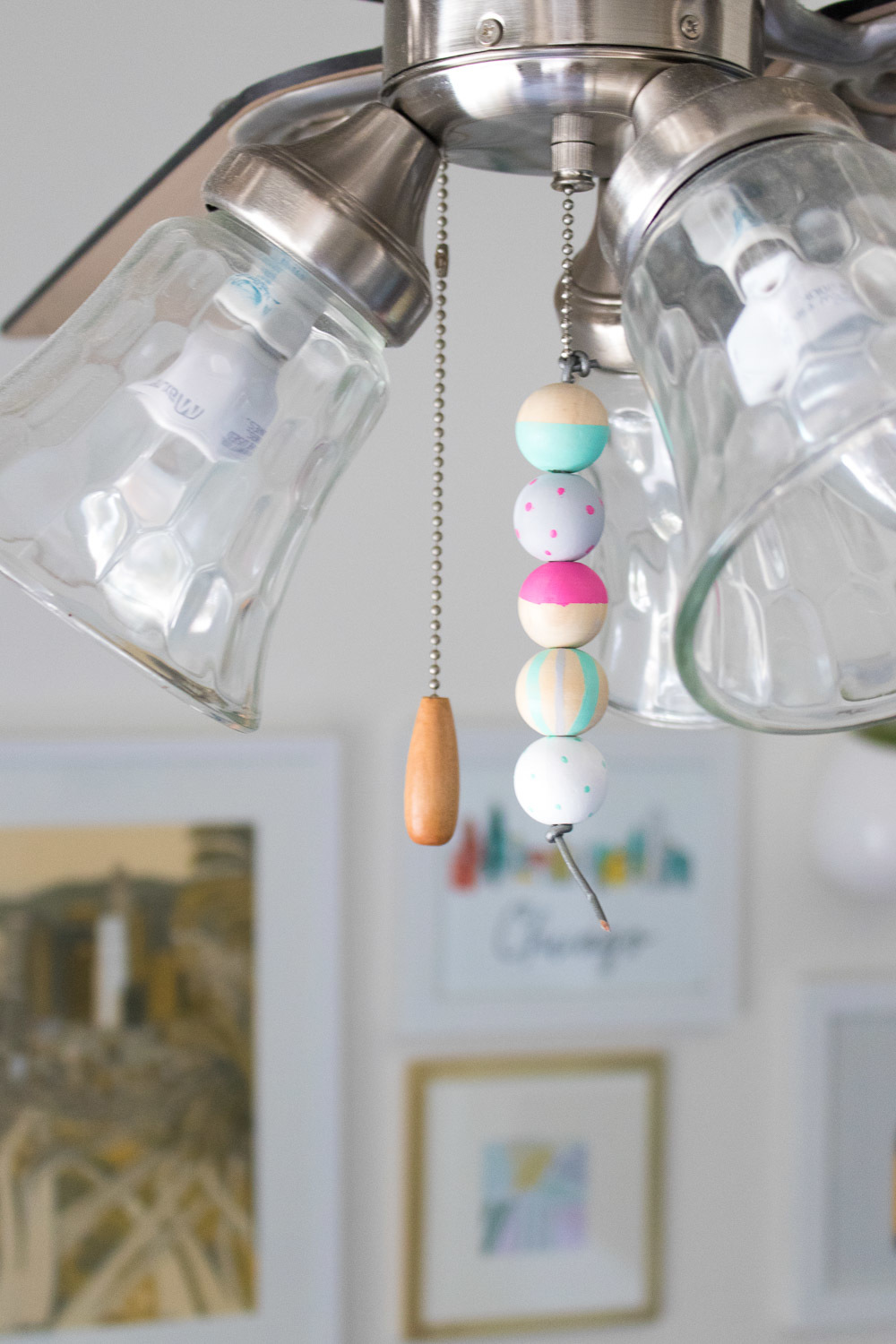 Balls are hanging from a cord of a ceiling light fixture.